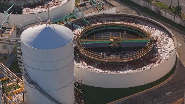Aerial view of a wastewater treatment plant with a large circular clarifier and storage tank in an industrial facility in Santo Domingo, Distrito Nacional, Dominican Republic.