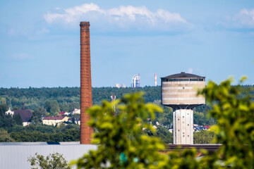 Na zdjęciu widać starą hutę w Ostrowcu Świętokrzyskim (z miastem w tle) oraz cementownię w Ożarowie. Na pierwszym planie dominują wysoki ceglany komin oraz cylindryczna, betonowa wieża ciśnień.  © Grzegorz