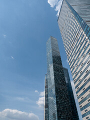 Fototapeta premium Modern glass skyscrapers with reflective facades rising against a clear blue sky in an urban setting