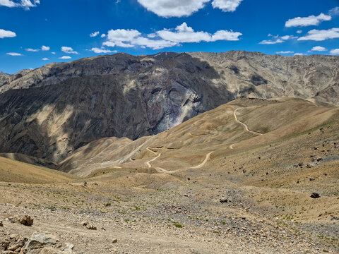 View of the winding Penzi La road traversing the rugged, arid mountain landscape of Zanskar, Ladakh, India.