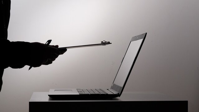 Silhouette of a person holding a clipboard and pen. Working with a laptop computer. Representing tasks. Data entry. Digital transformation. And professional productivity in a modern office environment