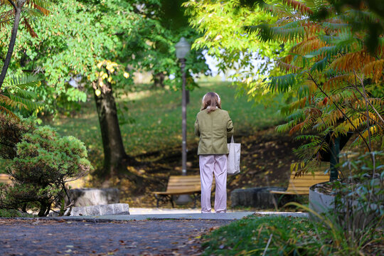 Femme seule marchant dans parc urbain en automne. Vue de dos. Une promenade en automne.	
