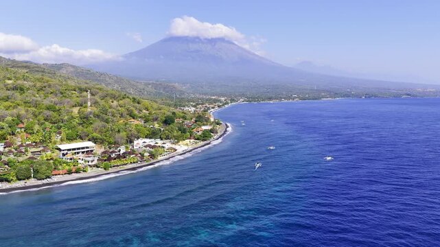Aerial drone view of Jemeluk Bay in Amed, Bali, Indonesia, showing the blue sea, coastal shoreline, beach and surrounding landscape