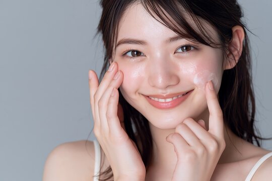 幸せな笑顔で美肌ケアする若い日本人女性の美容液を使ったスキンケア