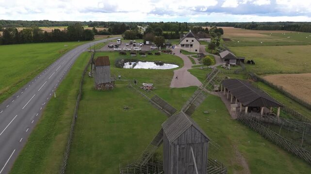 Aerial view of historic wooden windmills in Angla Windmill Park surrounded by green fields and a road in Saare County, Estonia.