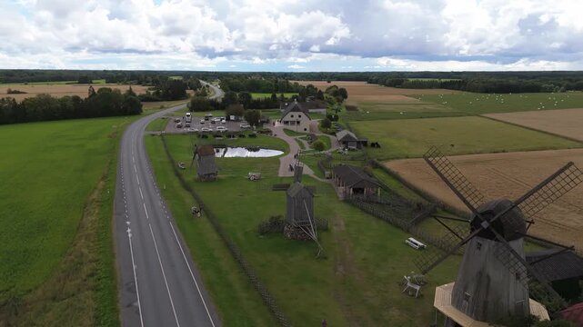 Aerial view of historic wooden windmills at Angla Windmill Park surrounded by green fields and meadows in Saaremaa, Saare County, Estonia.