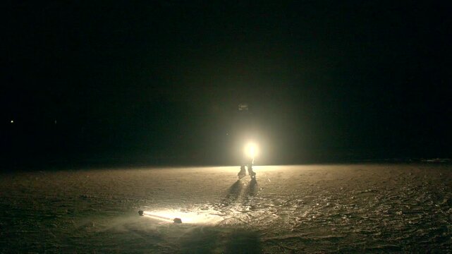 Skater under bright illumination. Frozen surface illuminated by vivid glow. Dynamic scene of skater nearing intense circular light on icy plain during cinematic moment