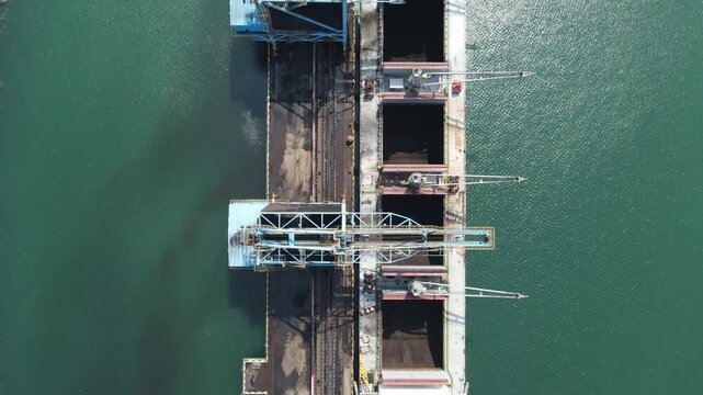 Aerial view of industrial loading cranes at a port facility in Cilacap, Central Java, Indonesia.