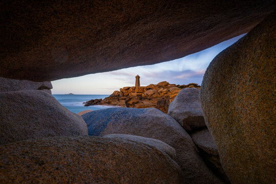 View of the Ploumanac'h lighthouse framed by large granite boulders on the coast in Perros-Guirec, Brittany, France.
