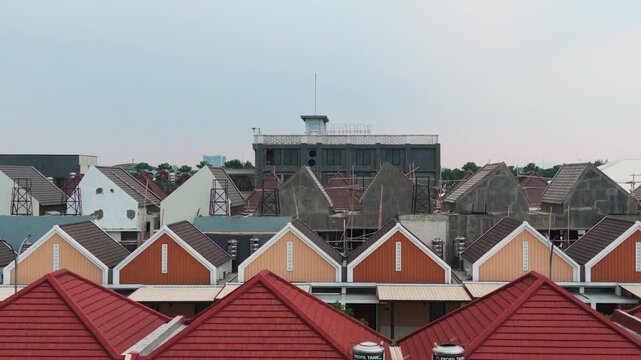 Aerial view of residential houses with colorful gabled roofs and construction scaffolding in a suburban neighborhood in Malang, East Java, Indonesia.