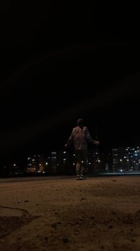 Nocturnal freestyle skipping street performance vertical stock video. Vertical lowangle view of performer skipping and spinning with lively tempo on open plaza, apartment windows