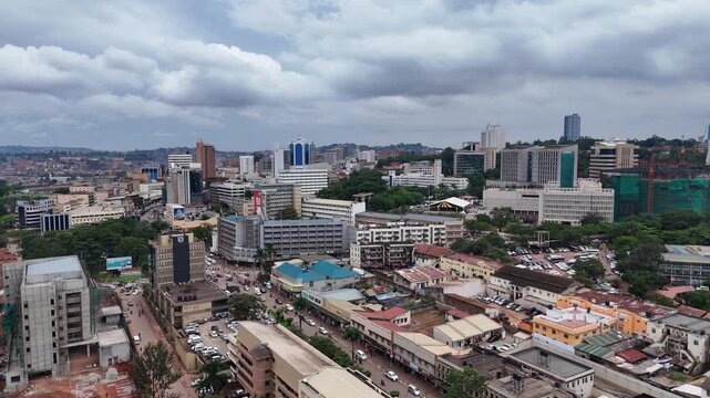 Aerial view of the bustling cityscape of Kampala with modern office buildings, dense urban development, and busy streets under a cloudy sky in Kampala, Central Region, Uganda.