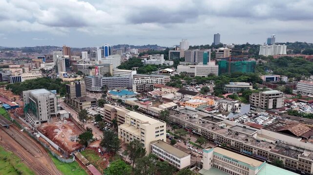 Aerial view of Kampala cityscape with urban buildings, roads, and railway tracks under a cloudy sky in Kampala, Central Region, Uganda.
