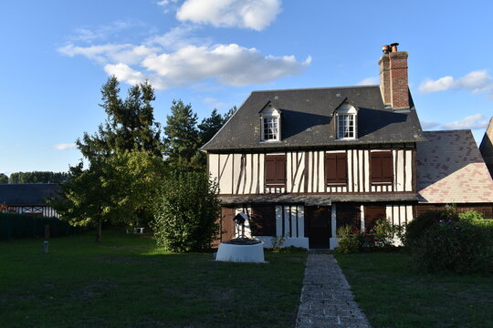 Maison normande authentique &agrave; colombages avec volets en bois et vieux puits &agrave; Vieux-Port en Normandie.