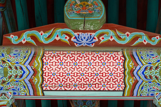 Korean traditional wooden temple roof eave with vintage colorful dancheong lotus and monster mask pattern for architectural background.