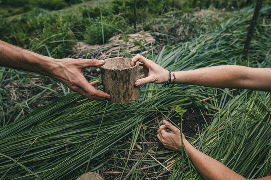 View of two people holding a rustic bamboo cup in a lush green field in Puerto Viejo de Talamanca, Limon Province, Costa Rica.