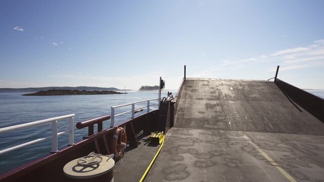 Deer Island Ferry cruising across calm ocean waters with its bow ramp raised, approaching forested islands in New Brunswick, Canada.