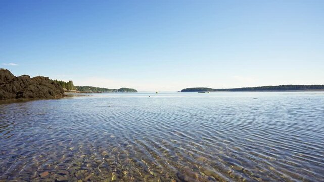 Clear shallow coastal waters rippling over a pebbled shoreline along Passamaquoddy Bay in Deer Island, New Brunswick.