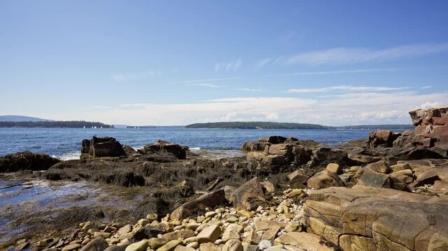 Granite boulders and cobble shore along Schoodic Peninsula looking out across Frenchman Bay toward Mount Desert Island in Acadia National Park, Maine.