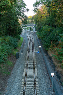 View of railway tracks leading into a tunnel surrounded by lush green trees and foliage in Prague, Prague, Czechia.