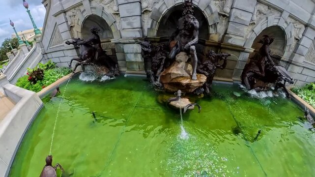 Slow motion 4K video pulls away from Neptune sculpture toward turtles and green water.
