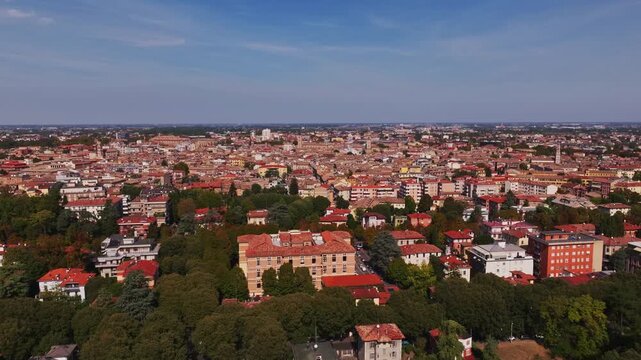 Aerial drone view of Parma, Italy, showcasing the historic city center, terracotta rooftops, churches, green spaces, urban architecture, and the Emilia-Romagna cityscape.