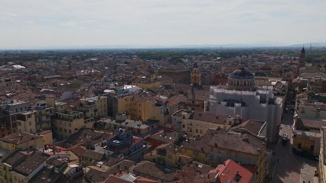 Aerial drone view of Parma, Italy, showcasing the historic city center, terracotta rooftops, churches, green spaces, urban architecture, and the Emilia-Romagna cityscape.