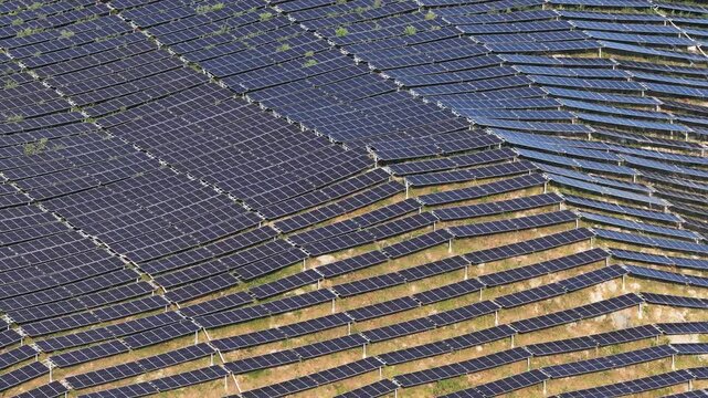 Aerial view of a large-scale solar farm with rows of photovoltaic panels installed on a hillside in Anshun, Guizhou, China.