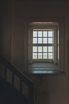 View of the window inside the historic Kopu Lighthouse, showing a grid frame and a glimpse of the surrounding landscape in Magipe, Hiiu maakond, Estonia.