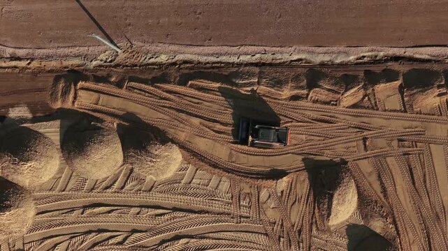 Aerial view of a construction vehicle working on a sandy site with tire tracks in Enschede, Overijssel, Netherlands.