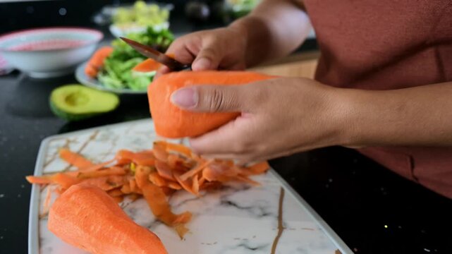 Person peeling a large carrot in the kitchen