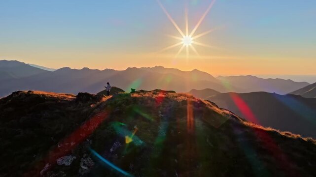 Aerial view of a person standing on the ridge of Col d'Aubisque during sunset with golden light over the mountain peaks in Beost, Nouvelle-Aquitaine, France.