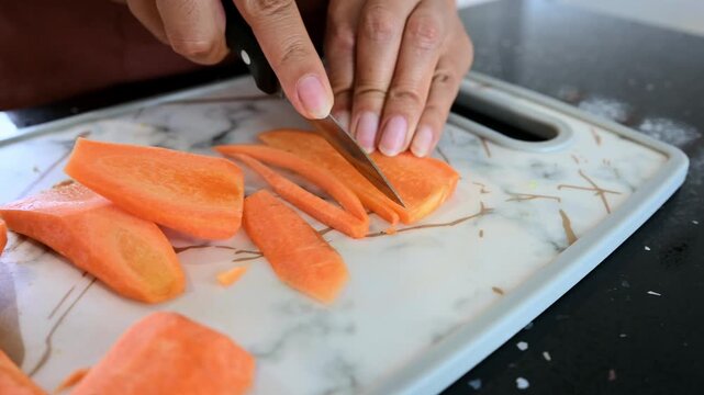 Woman's hands slicing fresh carrots into strips