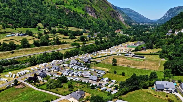 Aerial view of a campsite nestled in the valley near Col d'Aubisque, featuring rows of caravans, green fields, and surrounding mountains in Beost, Nouvelle-Aquitaine, France.