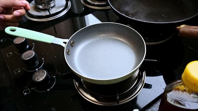 Person cooking fresh blueberries in a frying pan for homemade jam