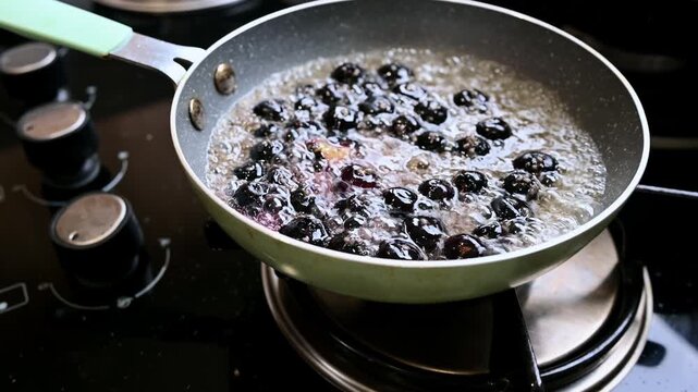 Preparing blueberry jam with sugar in a pan on the stove