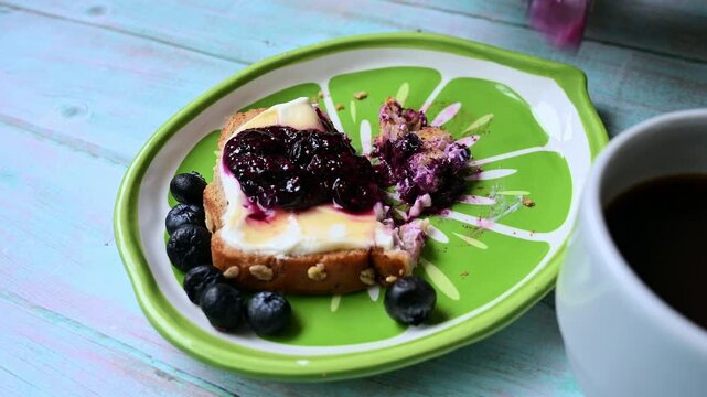 Woman cutting a blueberry jam with yogurt toast for breakfast