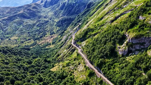 Aerial view of the winding road at Col d'Aubisque mountain pass surrounded by lush green slopes and dense forests in Beost, Nouvelle-Aquitaine, France.