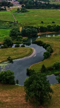 Aerial view of winding river flowing through lush green fields and trees in Bergheim, Nordrhein-Westfalen, Germany.