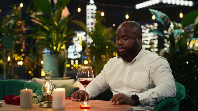 Annoyed boyfriend waits for his girlfriend at a restaurant and leaves after losing patience; upset man sits alone at a rooftop dinner table checking his wristwatch in frustration after being stood up.