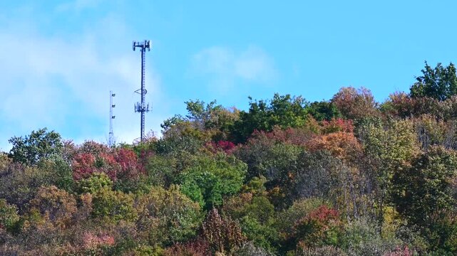 5G cellphone tower on top of a hill mountain fall backgrounds, tree tops in the wind, selective focus zoom lens