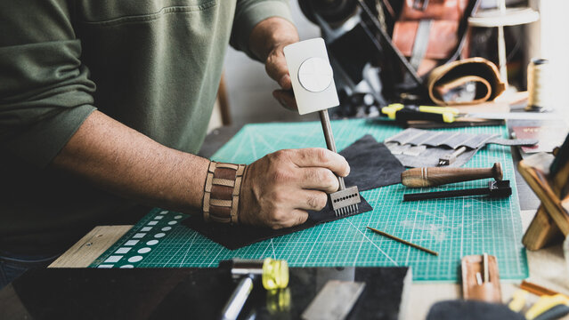 Artisan Using Mallet and Punch Tool on Leather in Workshop