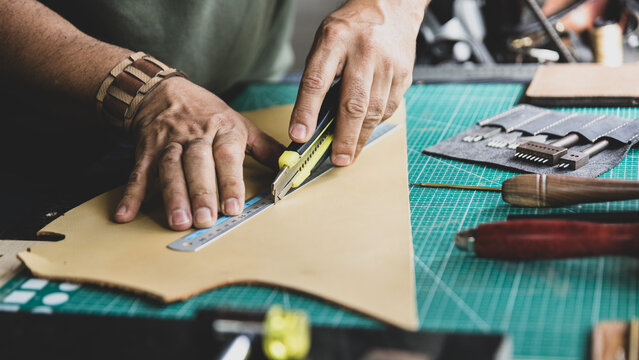 Artisan Hands Cutting Leather with Ruler and Knife