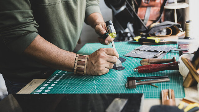 Artisan Using Mallet and Punch Tool on Leather in Workshop