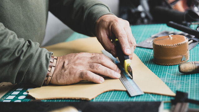 Artisan Hands Cutting Leather with Ruler and Knife