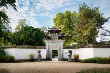 View of the traditional Chinese entrance gate with stone guardian lions and white wall in Bethmannpark in Frankfurt, Germany © gehapromo