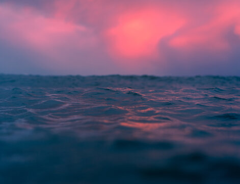 View of ocean waves under a vibrant pink and purple sunset sky in the United Kingdom.