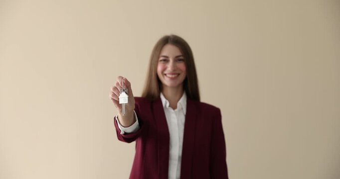 Woman with key near beige wall indoors. Office rent