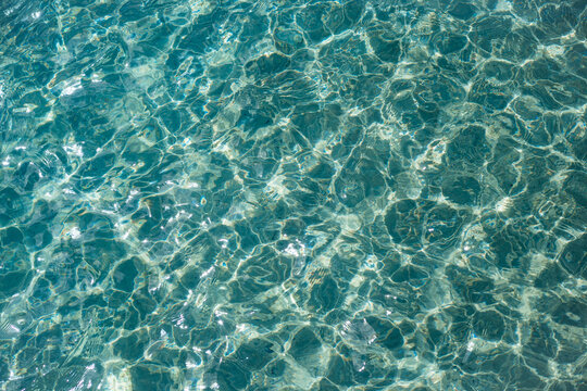 View of clear turquoise water with sunlight reflecting on the rippling surface, United Kingdom.