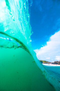 View of a turquoise ocean wave breaking with clear blue sky in the background in the United Kingdom.